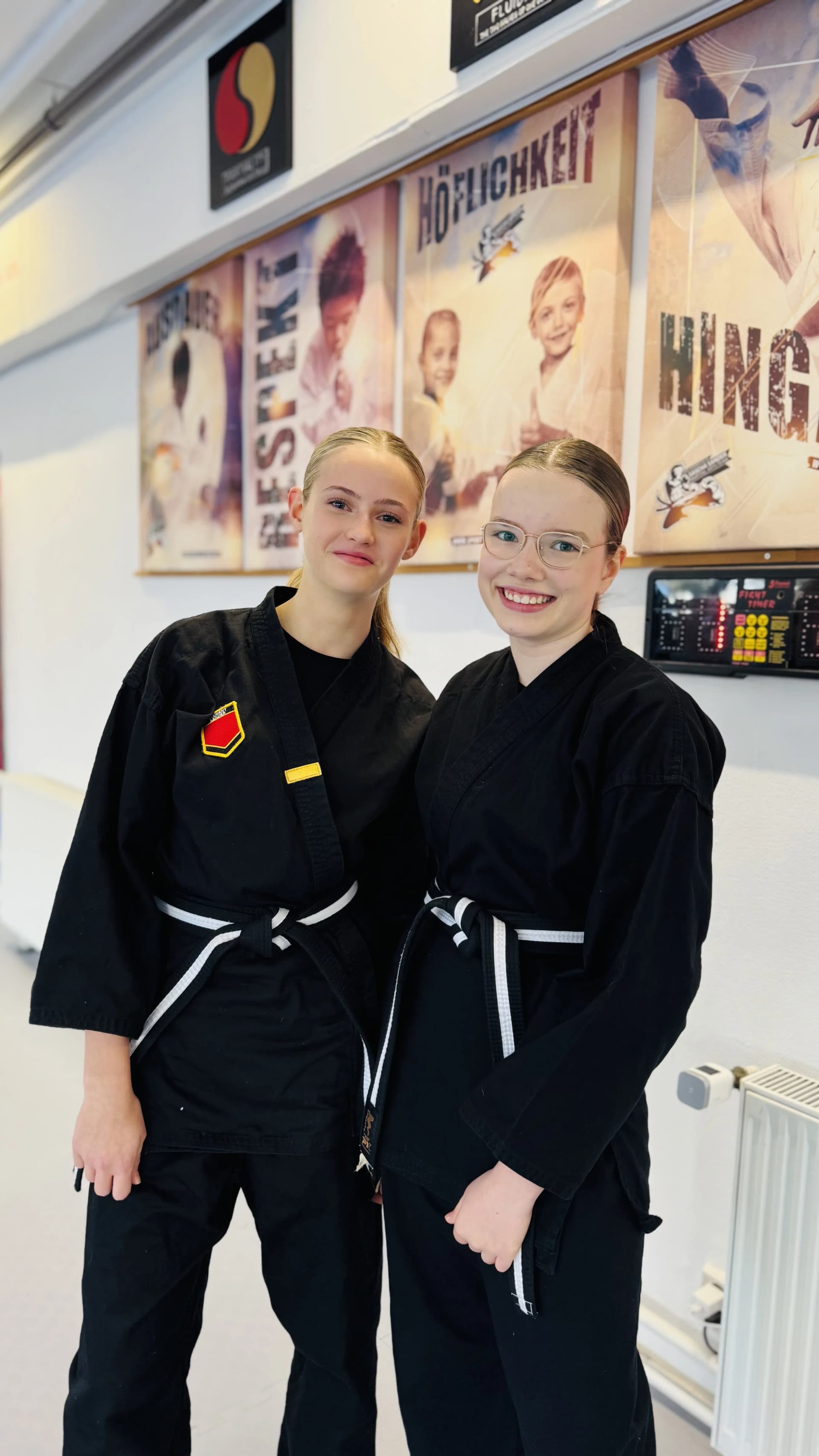 Jugendliche im schwarzen Inspire-Anzug konzentriert in Kampfkunst-Stellung im Dojo.
